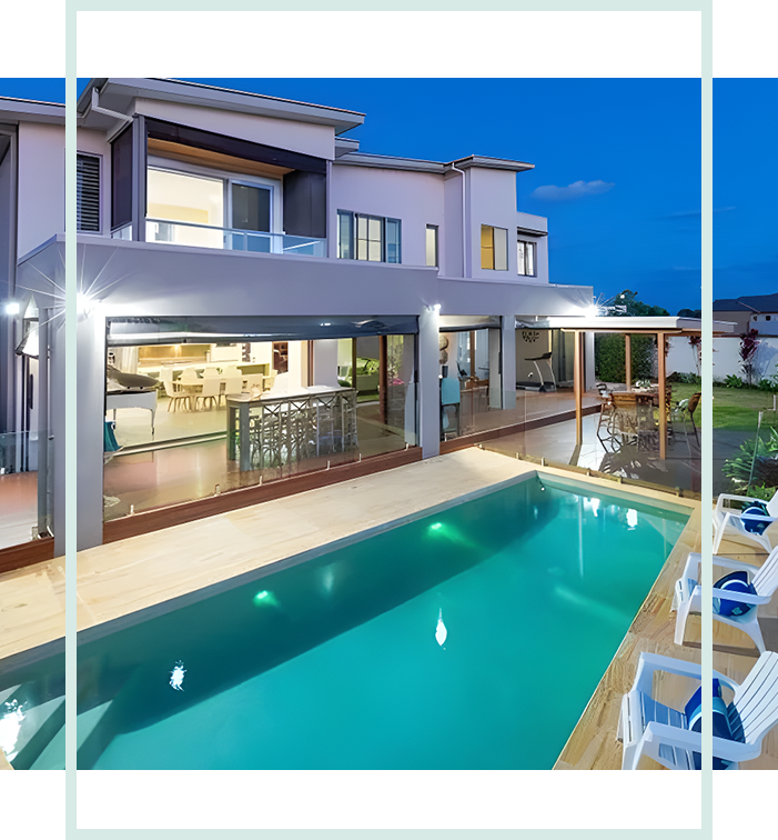 A pool and some chairs in front of a house.